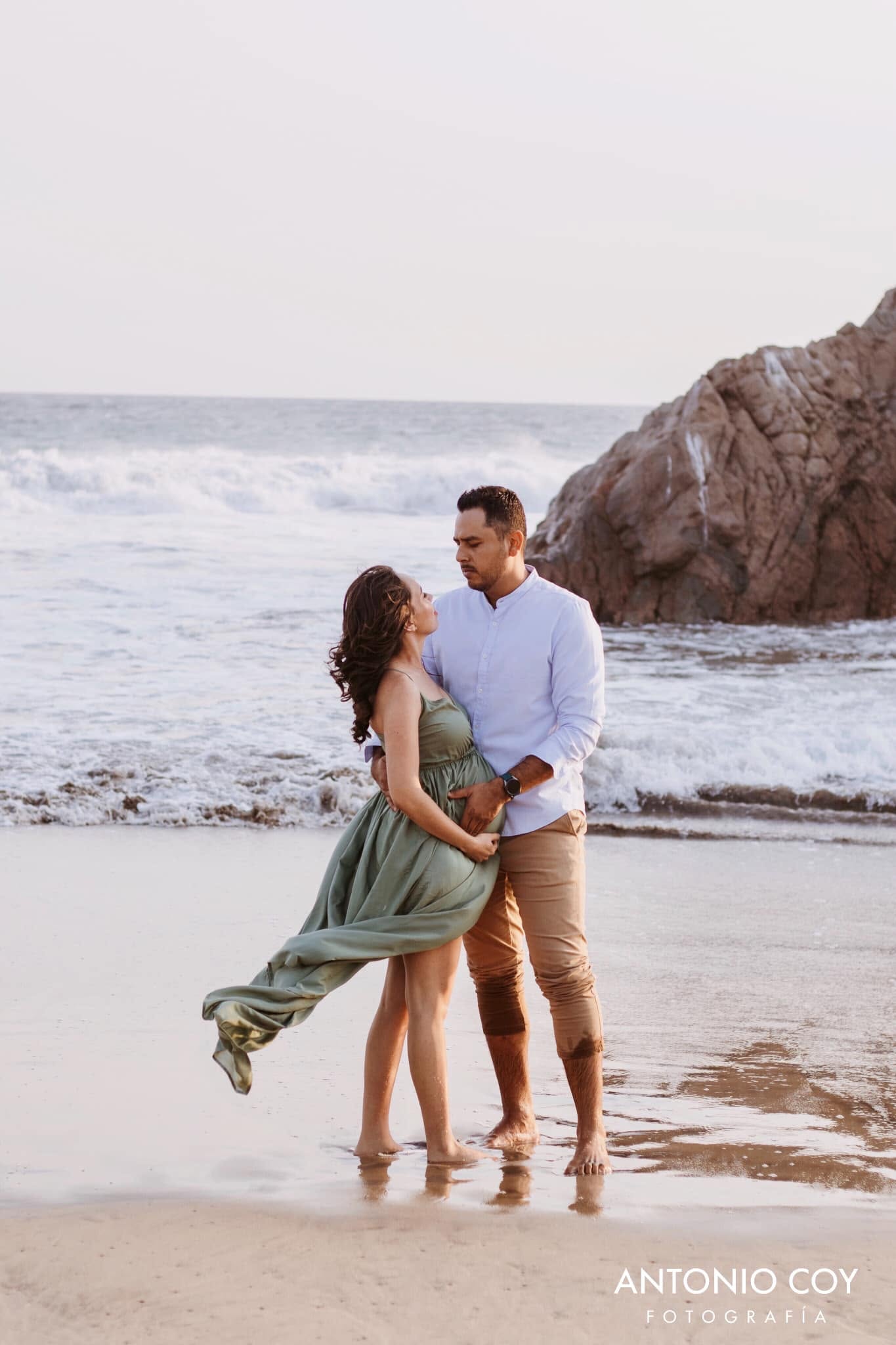 Pareja en la playa con vestido verde al viento